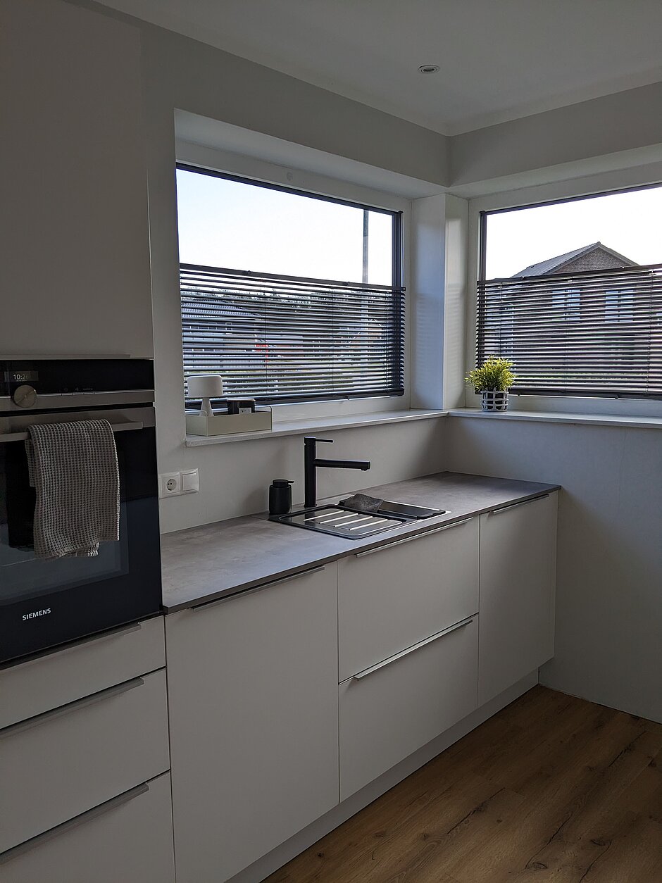Moderne und minimalistische Küche mit frei verschiebbarer Jalousie in schwarz.