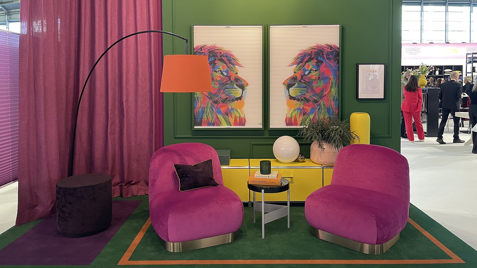 Modern gestalteter MHZ-Messestand mit bunten Plissees im Löwendesign, farbigen Sesseln und dekorativem Interieur in kräftigen Farben.