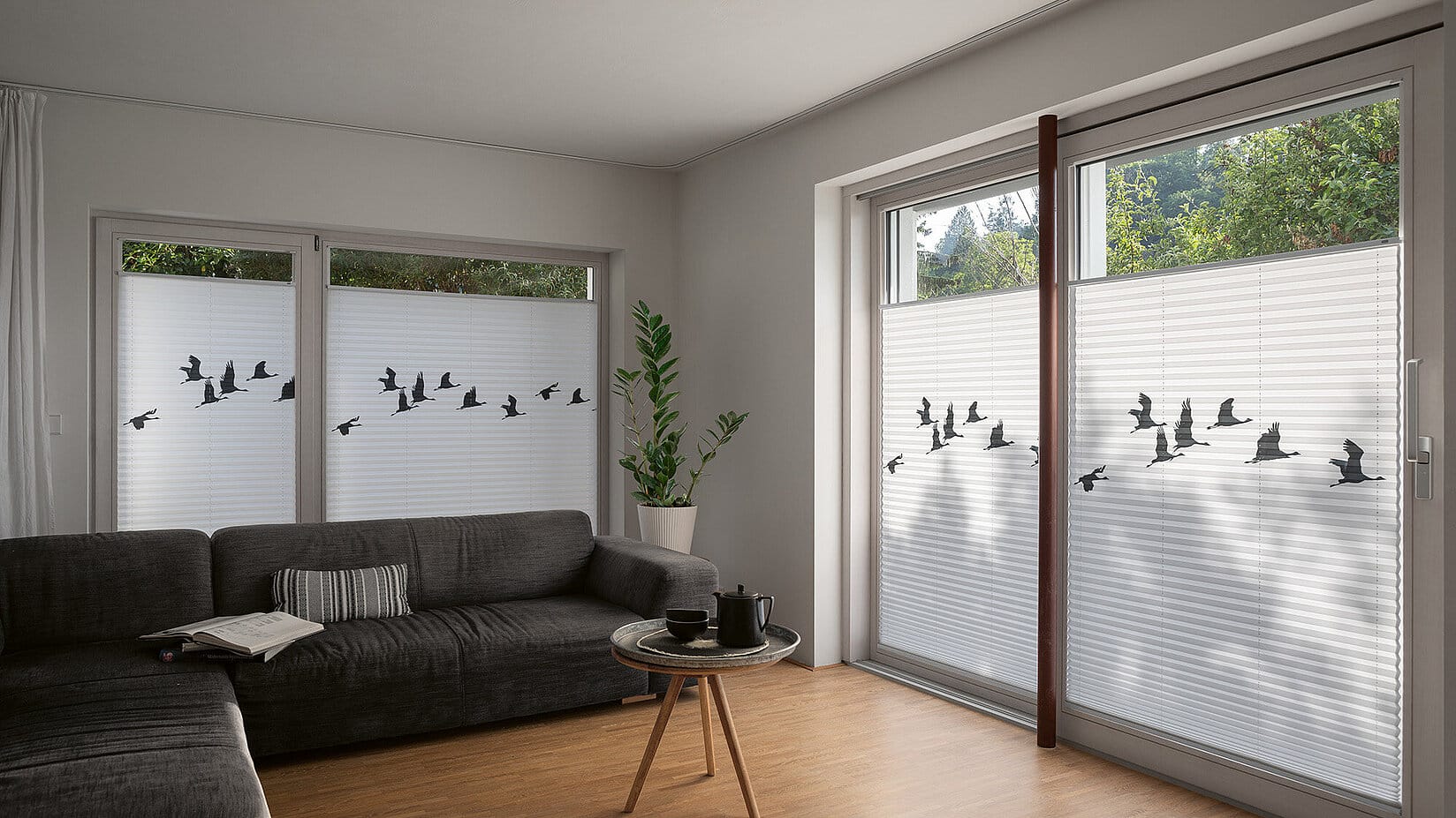 Wohnzimmer mit weissen Plissees mit schwarzen Kranichen als Motiv.