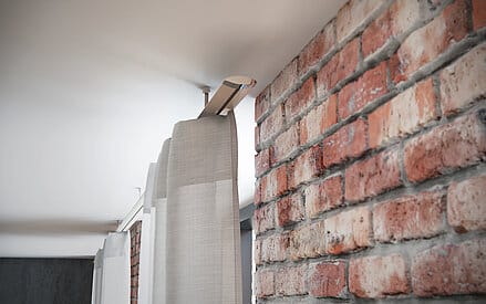 Vorhangstange mit hellem Vorhang als Sichtschutz vor einem Fenster