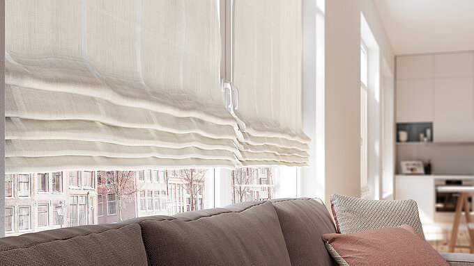 Helle, halbtransparente Raffrollos in einem modernen Wohnraum mit grossen Fenstern und gemütlicher Sofalandschaft.